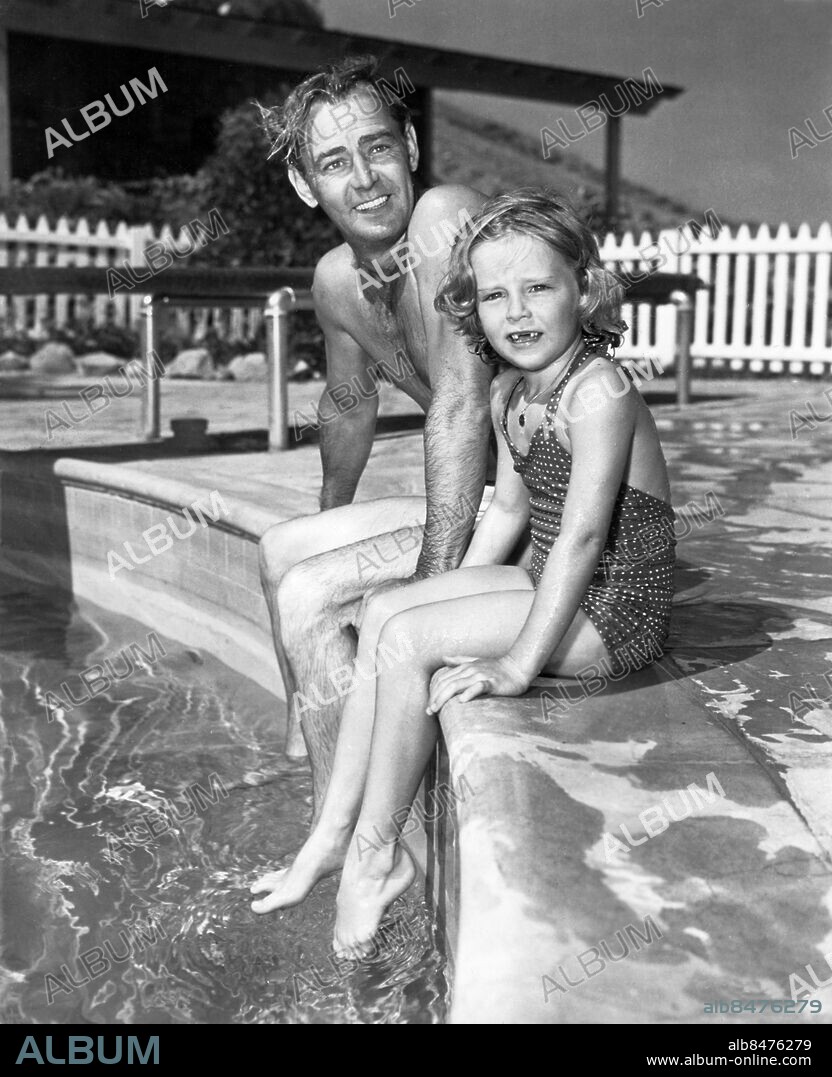 Orig. bildtext... SWIM-TIME WITH THE ALAN LADDS Hollywood, California. Alan Ladd, whose latest screen role is that of a two-fisted postal inspector in United States Mail takes time out from his studio assignements to instruct his son David, 3, and daughter Alana, 7 in the art of swimming sans water wings. (...) Pop and daughter take a breather at the pool's edge. Anm. För fullständig text se originalet Swimmingpool Pooler Baddräkter Skådespelare Glugg Tänder Dotter CD351 persons: ALANA LADD;ALAN LADD sites: HOLLYWOOD;USA.
