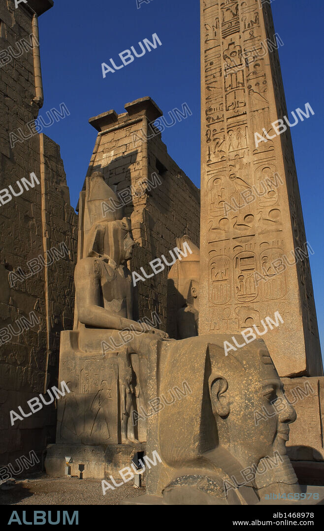 ARTE EGIPCIO. EGIPTO. TEMPLO DE LUXOR. Vista parcial del PRIMER PILONO del templo. Destacan los restos de un obelisco de granito rosado, y la cabeza y estatua colosal de RAMSES II (Tercer faraón de la XIX Dinastía del Imperio Nuevo, que gobernó de (1279-1213 a. C.). Antigua Tebas "Waset".