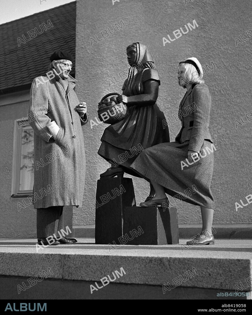 STOCKHOLM 1950. Bror Hjorth konstnär, vid sitt konstverk Flicka med fruktkorgutanför kommunalhuset i Huddinge med Birgitta Larsson som var modell till skulpturen.. Foto: TT Historical / Kod: 1902.