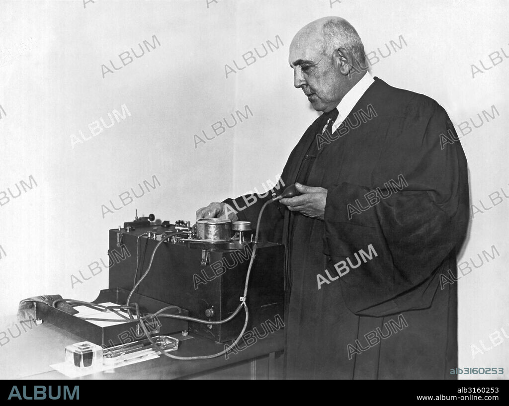 New York, New York: c. 1926. Judge Cornelius Collins examining the new psychogalvanograph machine used to test emotional reactions at the 'Crime Clinic' in the Criminal Courts Building.