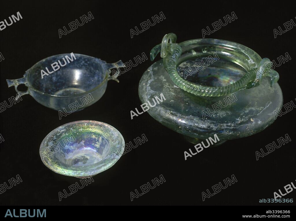 Conjunto de vidrio romano. De izquierda a derecha: plato, copa para beber (scyphos) (siglo I d. C.) y cuenco bicónico de asa torsa (mediados siglo I d. C.). Museo Nacional de Arte Romano. Mérida. Provincia de Badajoz. Extremadura. España.