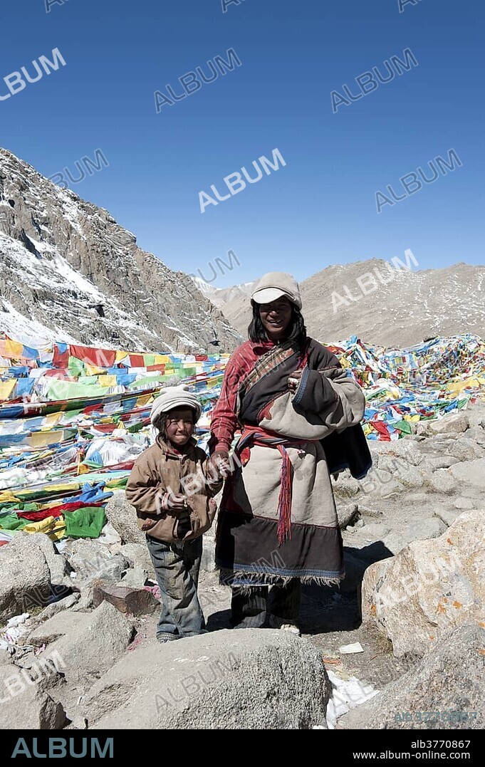 Tibetan Buddhist, pilgrims at the Dolma La Pass, 5670 m, colorful prayer flags, father and son, pilgrimage route around the sacred Mount Kailash, writing on rock, Gang Rinpoche, Kora, Ngari, Gang-Tise Mountains, Trans-Himalaya, Himalayan, West Tibet, Tibet Autonomous Region, People's Republic of China, Asia.