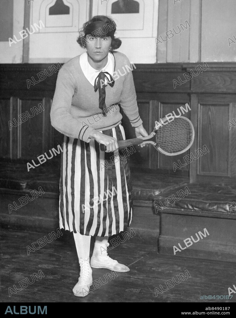 Orig. bildtext... MRS ROESER WINS WOMEN'S METROPOLITAN INDOOR TENNIS CHAMPIONSHIP Mrs Edna Hauselt Roeser today won the women's Metropolitan Indoor Tennis Championship by defeating Miss Alice Francis of Orange, N.J., the junior champion. The match was held at the 7th Regiment Armery in New York City. Photo of Mrs Roeser just after she had won the title. 2/28/25 Anm. Vinnare Tennisspelare Tennisracket Kjolar Randigt Ränder Rosetter CD499 persons: EDNA HAUSELT ROESER sites: USA;NEW YORK.