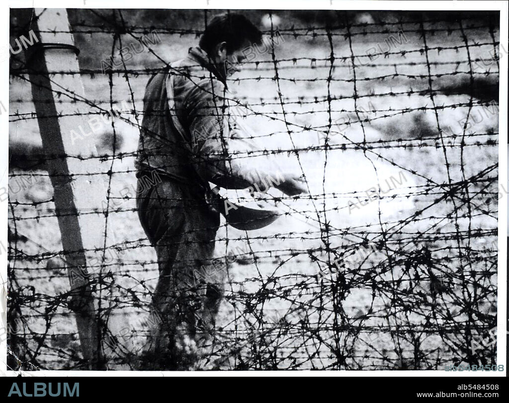 Berlin Wall Photo -  August 1961 - 'Death Strip' Although He Resembles A Farmer Sowing Seed, This East German Workman Is Sprinkling Chemicals to Kill Weeds in the 'Death Strip' Along The Communist Built Wall In East Berlin.