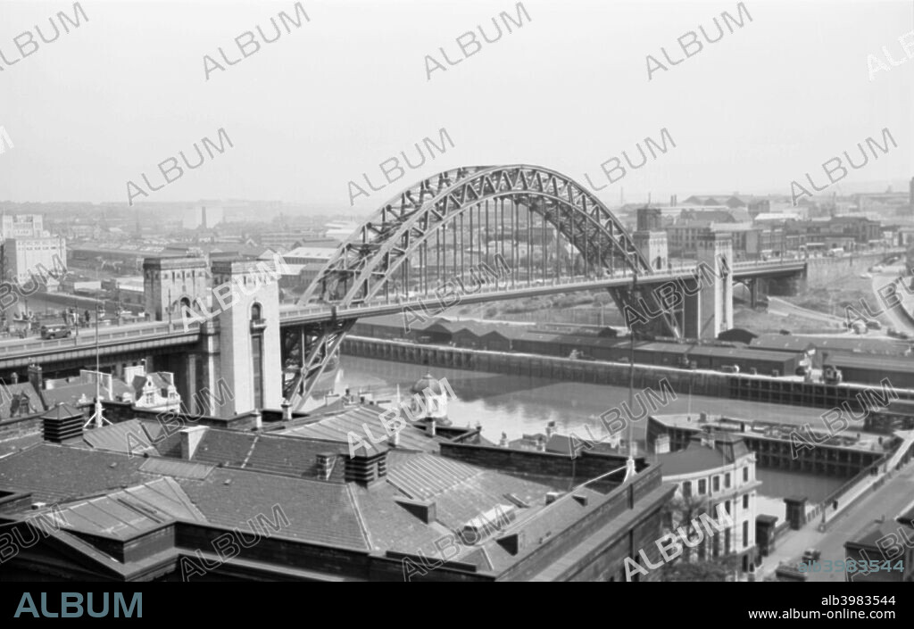 Tyne Bridge, Newcastle upon Tyne, Tyne and Wear, 1945-1980. Looking across the rooftops of Newcastle to the Tyne Bridge. The bridge is really called the George V Bridge and was opened by King George V and Queen Mary in 1928.