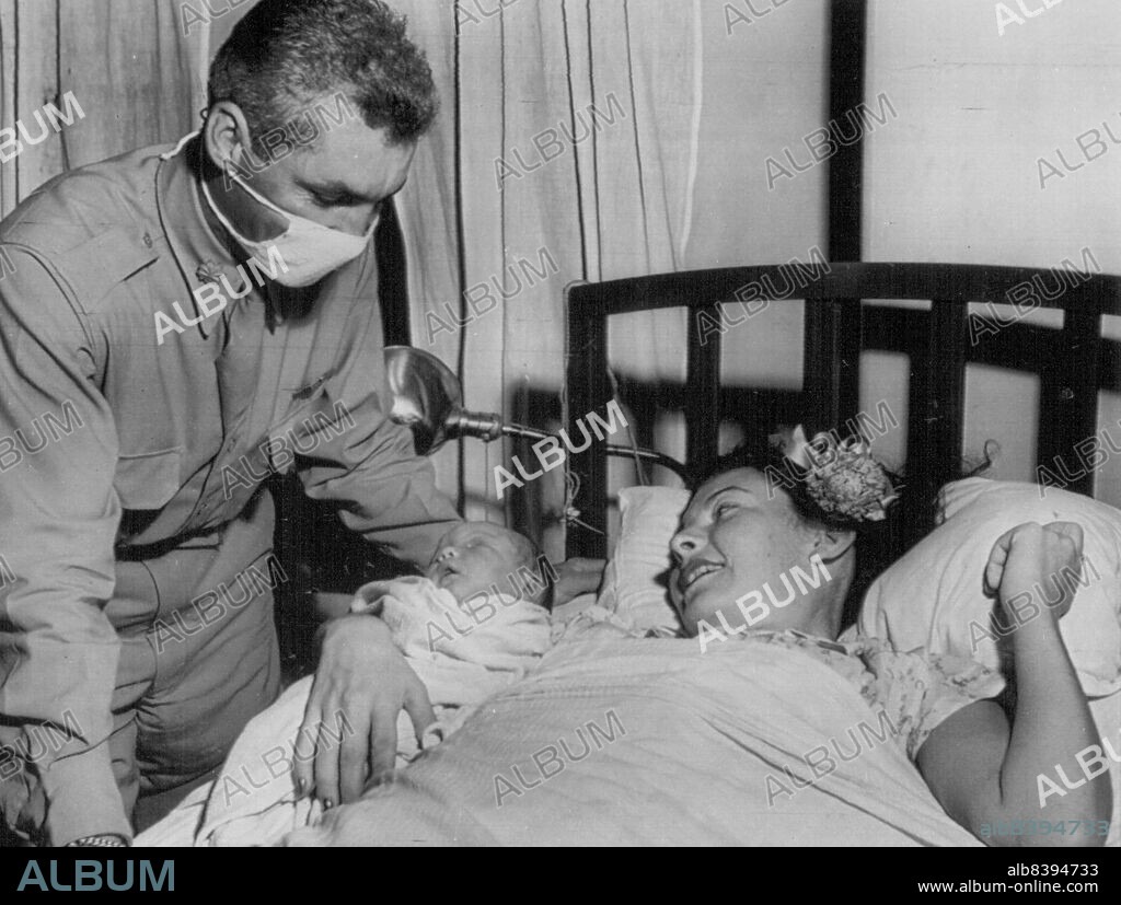 Major Swancutt Sees Son - Major W.P. Swancutt, operation Crossroads pilot, masked for baby's protection, and Mr. Swancutt look together for first time on their day-old son, Woodrow, Jr. July 13, 1946. (Photo by AP Wirephoto).
