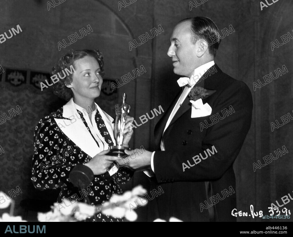 BETTE DAVIS y JACK WARNER (PRODUCTOR). 8ª Edición de los Premios Oscar (1936). Bette Davis premiada como mejor actriz por "Peligrosa". La acompaña el productor Jack Warner. 1936
