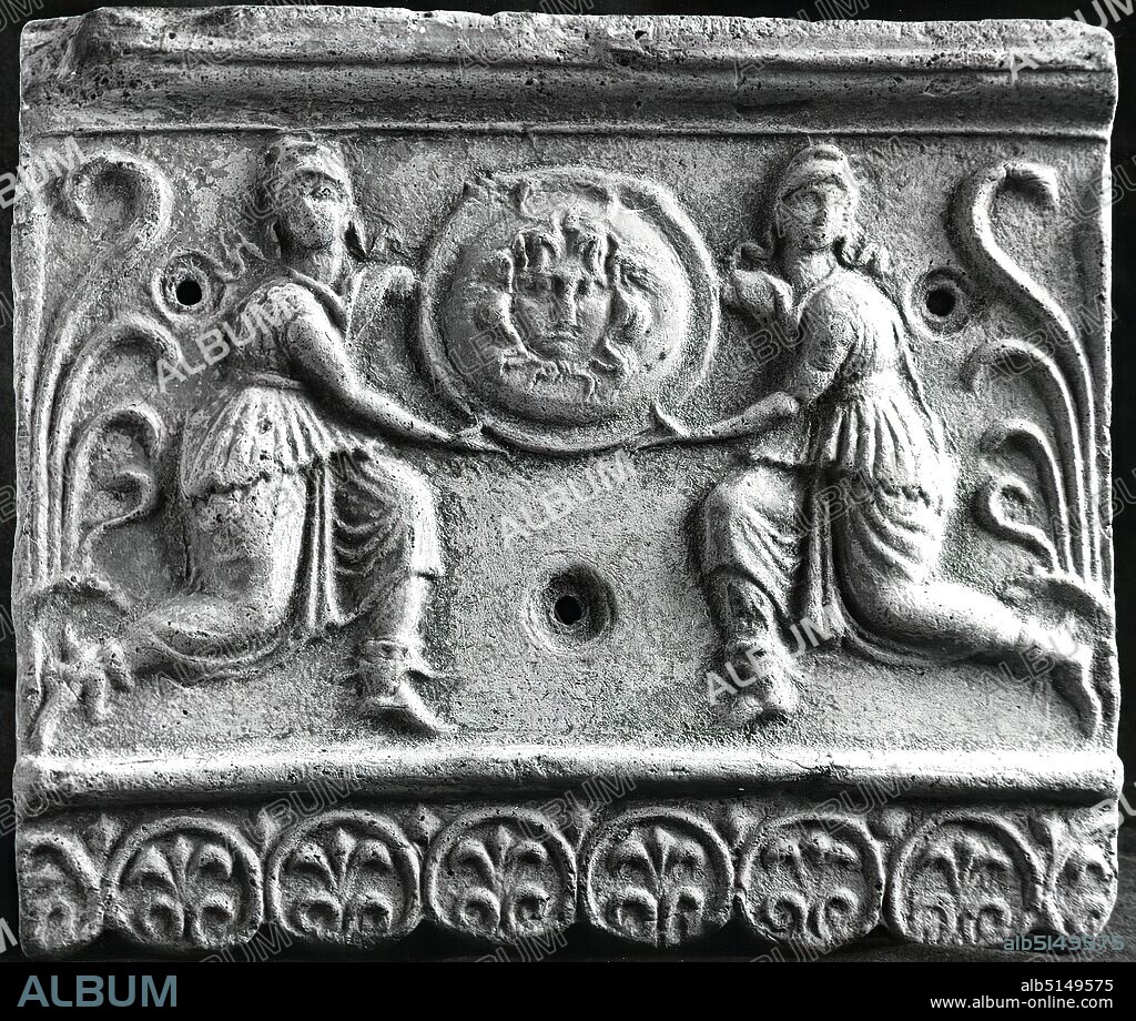 Architectural relief (Amazons with Gorgonian shield), clay, hand modeled, pressed, pressed into the mold, clay, Total: Height: 26 cm; Width: 31 cm, ceramics, architecture, Gorgons, Amazons, ornaments, Medusa head, High Hellenistic, Late Hellenistic, This architectural plate represents a preliminary stage of the so-called Campana reliefs. Comparable pieces were found in Metapont. The image field is closed at the bottom by a palmette band and at the top by a geison. To the left and right are half a palmette with a lancet leaf each, which prove that the plate was part of a repeat. Three holes in the picture field were formerly used for the attachment. No traces of paint have survived. Depicted are two Orientals standing opposite each other, kneeling and holding a round shield with a Gorgoneion. The Orientals are probably Amazons. They are dressed in long, belted robes, boots and Phrygian caps.