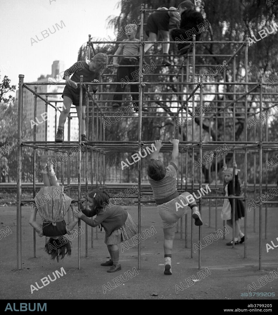 Editorial use only . Children climbing on monkey bars in Central Park playground. The jungle gym, monkey bars, or climbing frame, is a piece of playground equipment made of many pieces of material, such as metal pipe or rope, on which children can climb, hang, or sit. Photographed by Marjory Collins, October 1942.
