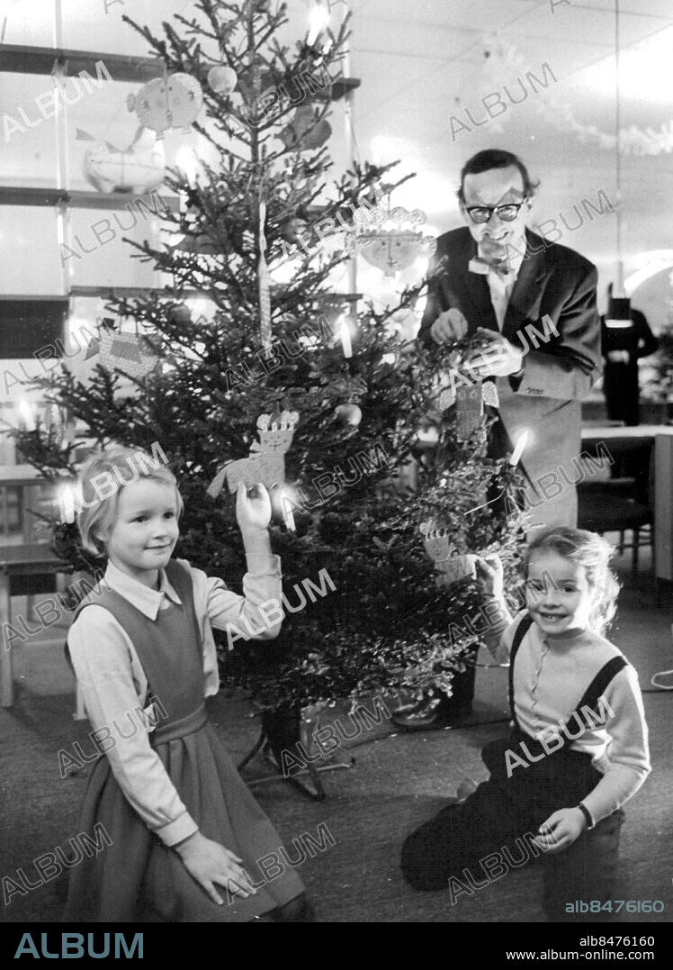 Stockholm 1960-12-04. Formgivaren Stig Lindberg och småflickorna Vibeke och Marita deltar i julgransklädning på NK. Foto: Sten Karsbrink / SvD / TT / kod 12014.