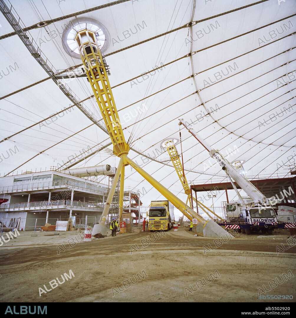 JOHN LAING PLC. Millennium Dome, Drawdock Road, Greenwich, London, 28/01/1999. An articulated lorry driving through the legs of one of the quadrapod bases to the pylons that support the roof structure at The Millennium Dome.