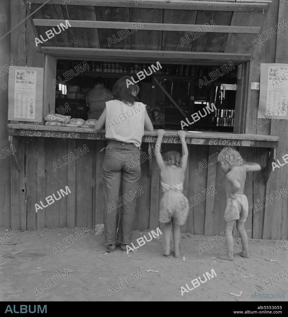 DOROTHEA LANGE. Hop picker with her children goes from paymaster's window to company-owned store adjoining. She had earned forty two cents that morning, spent it for one pound bologna sausage, one package "Sensation" cigarettes, one "mother's cake." Oregon, Josephine County, near Grants Pass.