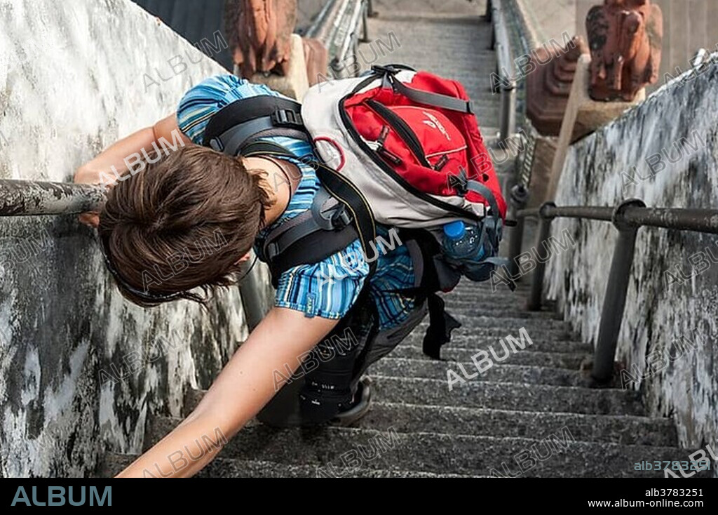 Woman climbing the stairs at Wat Arun, Temple of Dawn, Bangkok, Thailand, Asia.