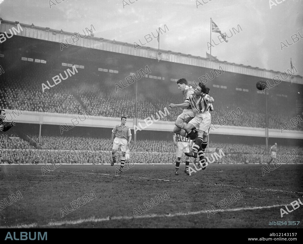 Arsenal centre forward Cliff Holton clashes with West Bromwich Albion defender during a bid for a high ball at the Arsenal V West Bromwich Albion match at Arsenal's Highbury stadium . 31 October 1953.