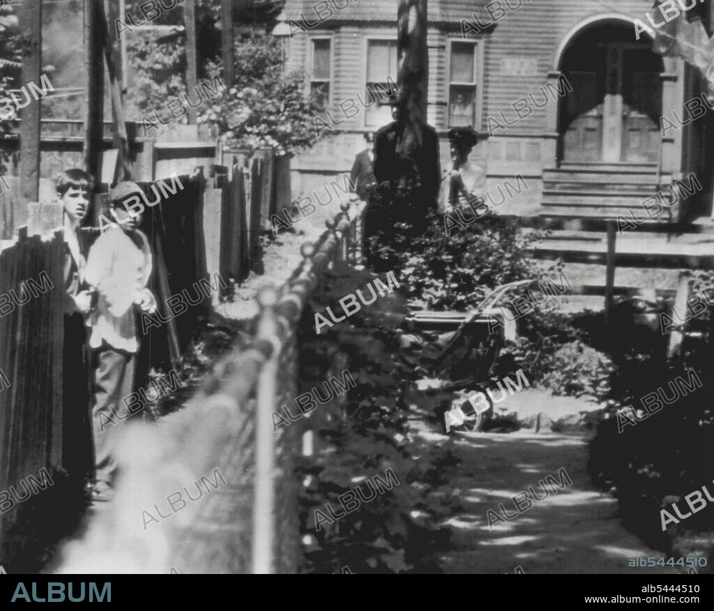 Boy Holds Police At Bay -- Edward Bancroft, 15, (left) holds revolver against side of William Rowan, 15, as a shield while three policemen take cover behind a telephone pole (right) at end of alley. Bancroft fired five times at police, injuring one patrolman when they sought to question him about a robbery. Rowan, playing in a nearby school yard, was forced to act as a hostage. A policeman crept behind fence and hit Bancroft on head with gun butt to end the skirmish. June 23, 1947. (Photo by AP Wirephoto).
