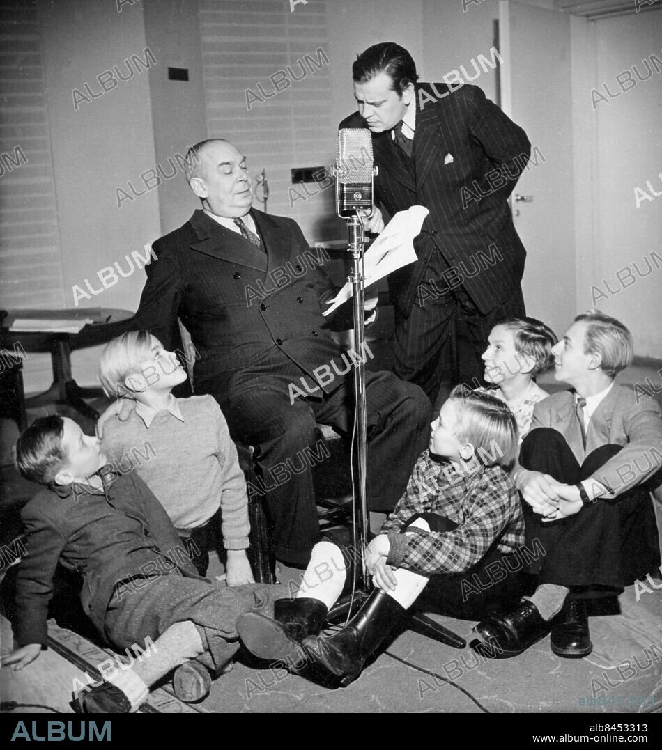 Orig. bildtext... PÅ JULTOMTENS EXPEDITION, reportage från Tomtelandet den 14 dec 1946 Sittande på golvet: tomtenissarna Lasse Sarri, Olle Adolphson, Björn Naeslund, Olle-Gösta Olsson och Hans Lindgren Reportern Karl Axel Arvidsson intervjuar tomtefar Ernst Brunman. Anm. Manus Publ i RiR 2/47 CD585 persons: ERNST BRUNMAN;KARL AXEL ARVIDSSON;HANS LINDGREN;OLLE-GÖSTA OLSSON;BJÖRN NAESLUND;OLLE ADOLPHSON;LASSE SARRI sites: SVERIGE.