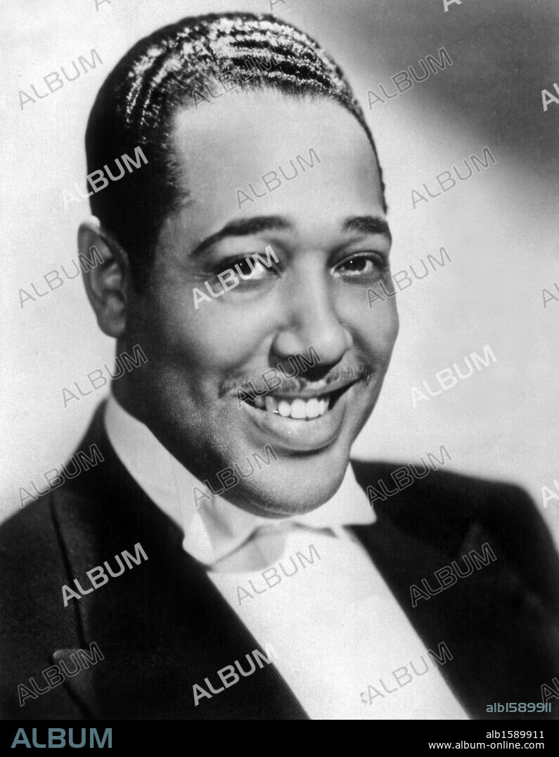 Headshot studio portrait of Amercian jazz pianist, composer and badleader Duke Ellington, wearing a tuxedo and a bow tie and smiling. 1937.