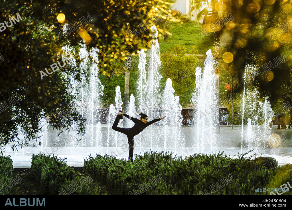 Woman practicing yoga, Riera Park, Palma, Mallorca, Balearic Islands, Spain.