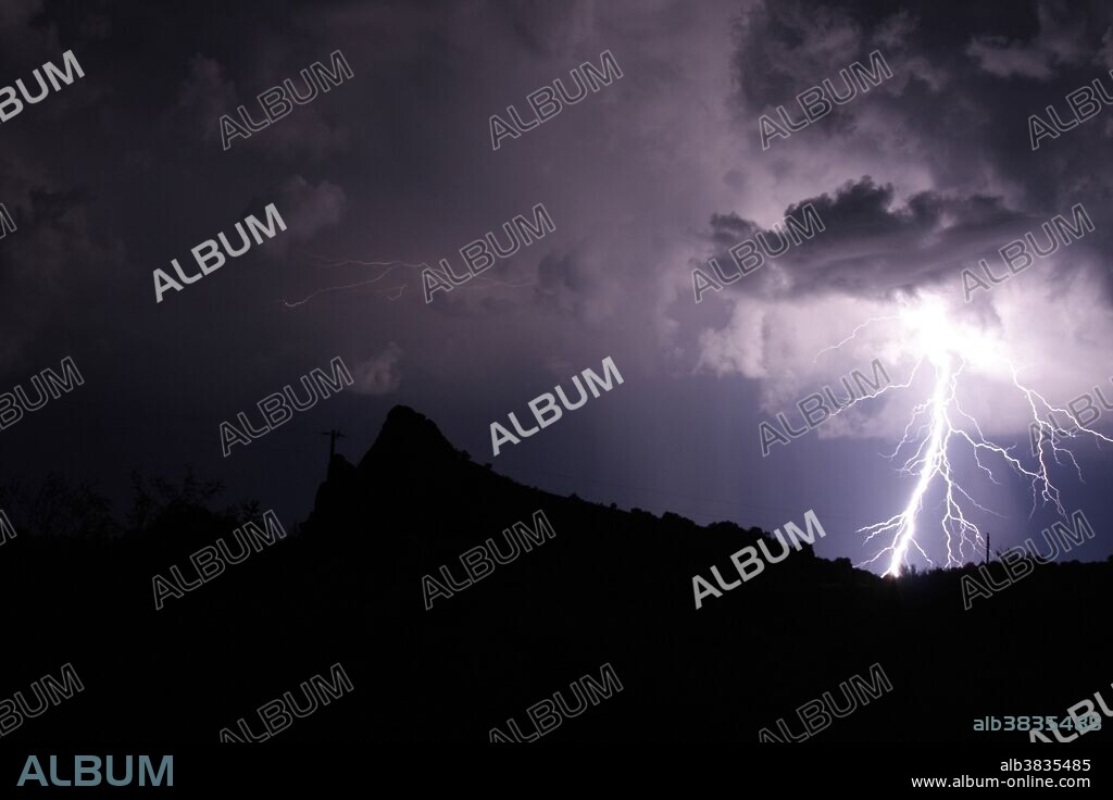 Lightning during a mountain thunderstorm in the Davis Mountains in western Texas. The low peak on the left is the remnant of an extinct volcano.