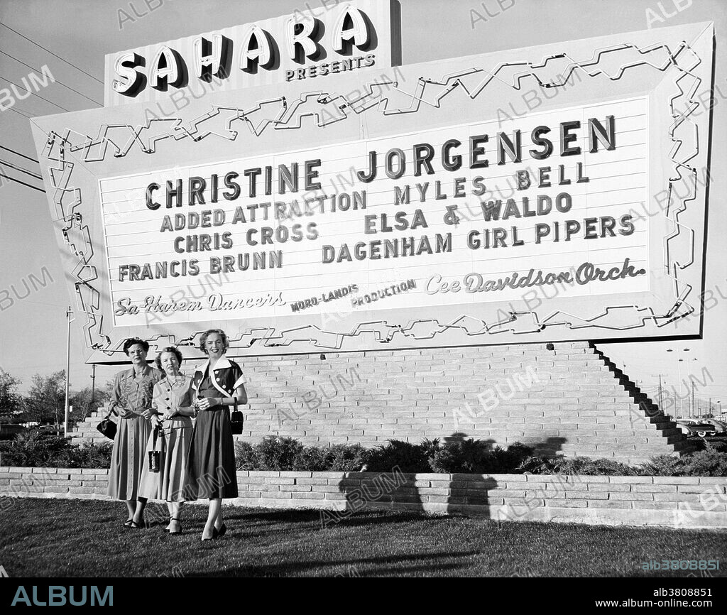 Christine Jorgensen (1926-1989), one of the first people to have sex reassignment surgery, and friends, standing in front of a sign advertising one of Jorgensen's shows.