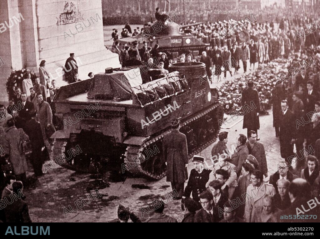 Black and white photograph of the funeral procession in honour of General Philippe Leclerc (1902-1947). His remains are transported on a tank under the Arc de Triomphe on their way to Les Invalides for burial.