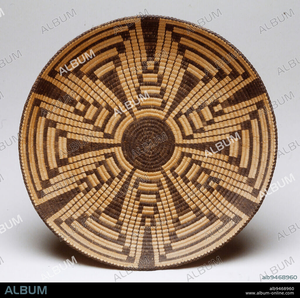Basket, 20th century, 2 x 12 in. (5.08 x 30.48 cm), Plant fibers, United States, 20th century, The art of basket making is passed through generations of Tohono Oodham and Akimel Oothom women. Young women learn by listening and watching their elders. They begin with simple designs and work their way to using more complex patterns. The complexity of each artists design is created entirely in a mental picture: it is never drawn beforehand. The maker counts only stitches to ensure a balanced pattern and perfectly straight or curved lines. Variations of the squash blossom design decorate these Akimel Oothom baskets. It is said that the squash plants once grew in the fields of ancient Akimel Oothom farmers. Another possibility is that the buttons on the trousers of Spanish soldiers originally inspired the design. The squash blossom also appears commonly as a form on Southwestern jewelry.