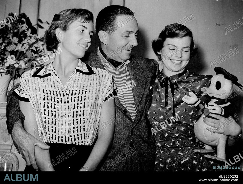 Donald Duck Here With Disneys - The Disney family, minus one, is here and Laughing. Present are father Walt, daughters Diane, in blouse decorated with water carriers, Sharon, in dress printed with galloping horses, and Donald Duck. Present, too, but out of the picture, is Mrs. Disney. She and the family reached London from Hollywood yesterday for Mr. Disney to film "Robin Hood" and plan "Peter Pan" "Don Quixote". June 22, 1951.