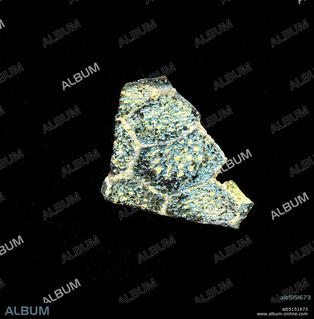 Fragment of a vessel, glass, millefiori technique, Total: Height: 2.90 cm; Width: 2.10 cm, container, storage, kitchen work, floral ornaments, Early Imperial Period, A slight curvature of the heavily weathered glass fragment allows the assignment to a vessel, possibly a bowl. On a presumably violet background, a grid can be seen, reminiscent of honeycombs, in which circularly arranged bright dots can be seen. For the production, different colored glasses were formed into tubes and rods. These were pressed together and heated, resulting in a long rod. The glass, now cut into slices, had different amorphous or floral patterns. Several of these plates were then folded together, heated again and pressed into a vessel form. Due to the complex manufacturing process and its fragility, glass was considered one of the luxury articles of antiquity.