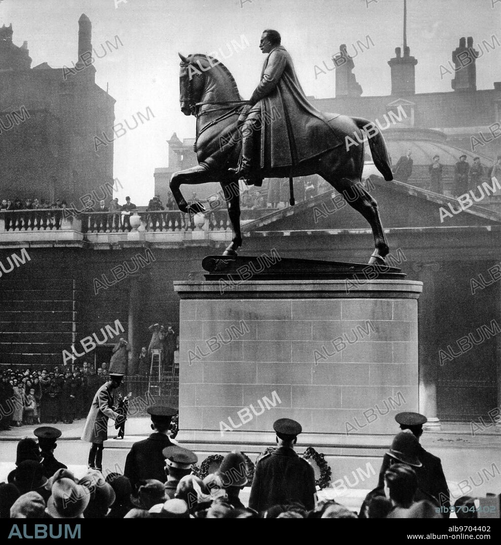 Earl Haig statue. Mr A F Hardiman's much-criticised statuen of Earl Haig at Whitehall. A view that shows the King placing his wreath beside it on Armistice day. The day after the Duke of Gloucester had unveiled it. 11 November 1937.