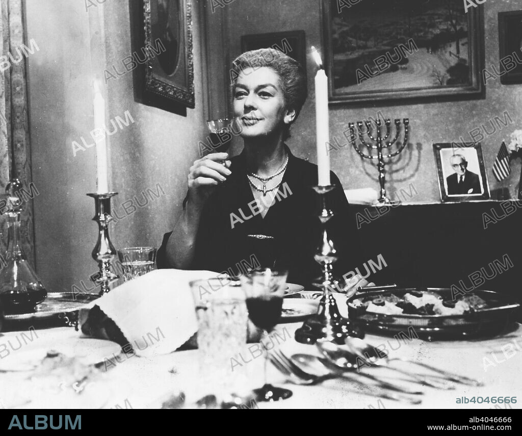 Rosalind Russell as Mrs Jacoby in A Majority of One, by Warner Brothers, 1962. Hollywood star Rosalind Russell (1907-1976) raises a glass at a table laid for a meal. In the background is a menorah, the seven-branched candlestick used for Jewish religious festivals. The film was a comedy about a romantic entanglement between a Jewish widow from Brooklyn and a Japanese industrial tycoon from Tokyo. Courtesy of Warner Bros Inc. For editorial uses only, all other uses to be cleared.