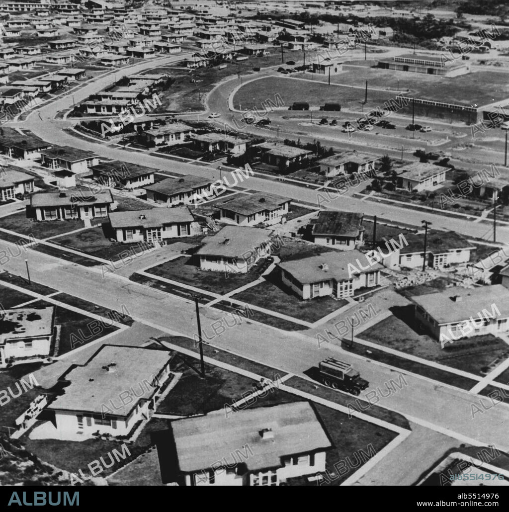 Okinawa: Ten Years Later -- This is the Okinawa U.S. troops stationed there know today. The aerial view shows a section of the suburban-like dependent-housing area at Sukiran. The homes are concrete typhoon-proof structures. The buildings at upper right house the commissary, bank and post office. May 06, 1955. (Photo by U.S. Army Photo).