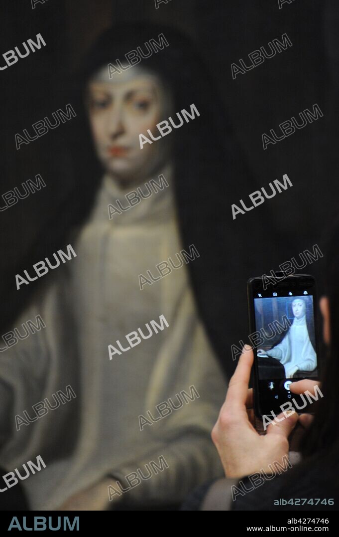 Detalle de la mano de una persona haciendo una fotografía con su teléfono móvil al retrato de Doña Mariana de Austria, pintado por Juan Carreño de Miranda (1614-1685). Real Academia de Bellas Artes de San Fernando. Madrid. España.