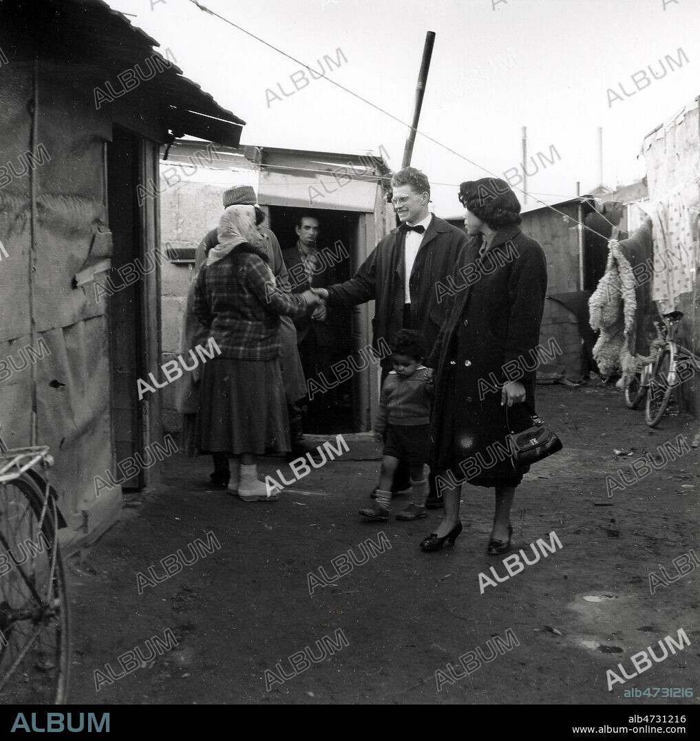 Claude Huet en visite dans le bidonville de Nanterre. Photographie Jean POTTIER de 1957. Credit : Coll. Jean Pottier / KHARBINE-TAPABOR.