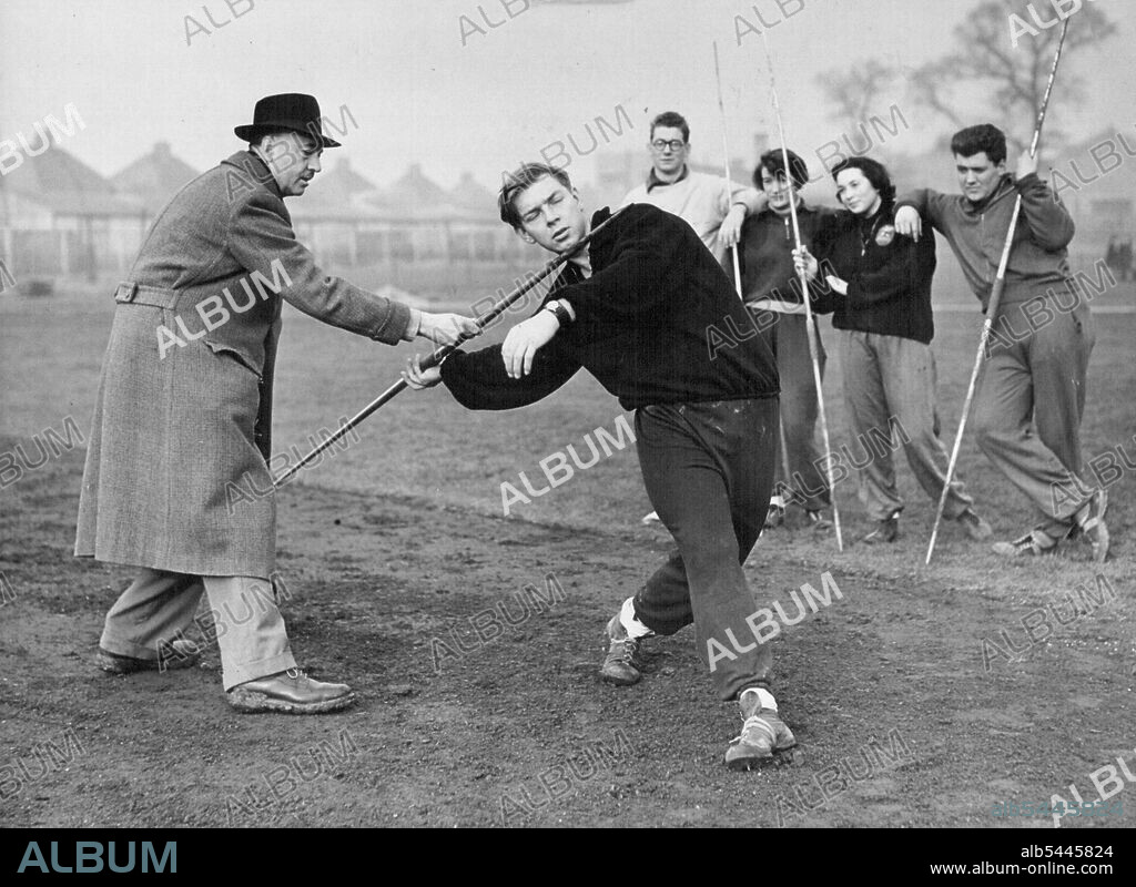 Young Athletes "Tune Up". 19-year-old Colin Tucker, of the Thames Valley Harriers, who is fast making a name for himself as a javelin thrower of merit, seen receiving a few hints from Mr. W.L. Plumridge the A.A.A. Honorary Senior Coach of the Thames Valley Harriers, during training at Alperton Sports Ground. Four other javelin throwers watching intently are (left to right) D. Tucker of the Thames Valley Harriers; M. Ruder of the London Olympiades: V. Kay of Middlesex Ladies: and D. Coulter. January 13, 1955. (Photo by Fox Photos).