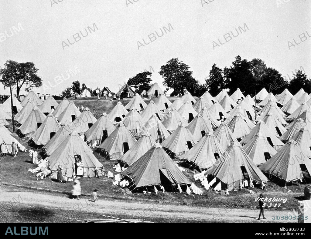 The Great Mississippi Flood of 1927 was the most destructive river flood in the history of the United States. The flood began when heavy rains pounded the central basin of the Mississippi in the summer of 1926. By September, the Mississippi's tributaries in Kansas and Iowa were swollen to capacity. Flooding overtook the levees causing the Mounds Landing to break with more than double the water volume of Niagara Falls. The Mississippi River broke out of its levee system in 145 places and flooded 27,000 square miles. This water flooded an area 50 miles wide and more than 99 miles long. The flood caused over $400 million in damages and killed 246 people in seven states. The flood affected Arkansas, Illinois, Kentucky, Louisiana, Mississippi, Missouri, Tennessee, Texas, Oklahoma and Kansas. By May 1927, the Mississippi River below Memphis, Tennessee, reached a width of 60 miles. Photo originally captioned: "The Great Mississippi River Flood of 1927. A refugee camp at Vicksburg, Mississippi, on May 3, 1927. This was a nice camp on high ground. Many refugees had to live on the levees for months until the water receded." Monthly Weather Review Supplement No. 29.