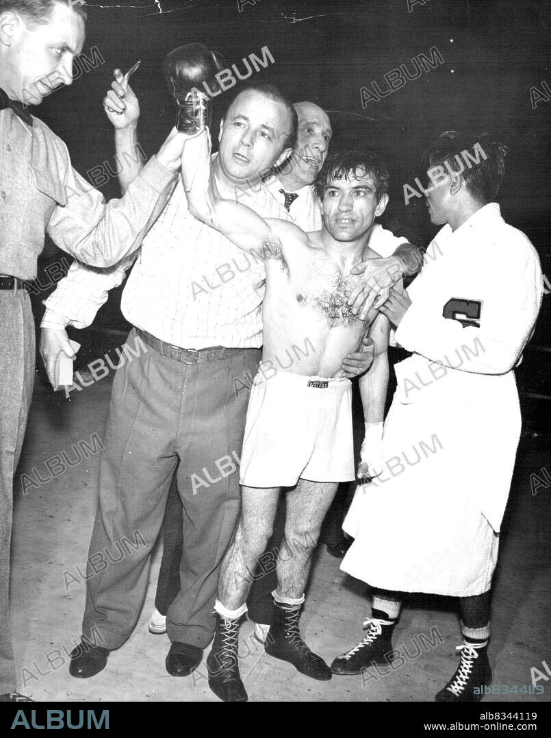 New Flyweight Champion -- Pascual Perez of Argentina has his hand raised in victory after winning the world flyweight championship in a unanimous decision over Japan's Yoshio Shirai (right) in a 15-round match at Tokyo (November 26th). Referee Jack Sullivan (left) holds up the winner's hand as Perez trainer Felipe Segura (background, center) and manager Lozaro Kooi (second from left) stand by. November 29, 1954. (Photo by United Press Photo).