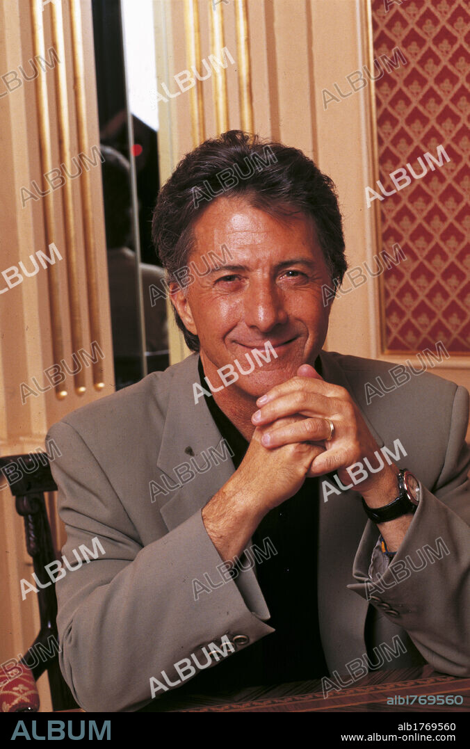 Artist Dustin Hoffman. Actor Dustin Hoffman, smiling, sitting on a desk, with his hands joined. 1993.