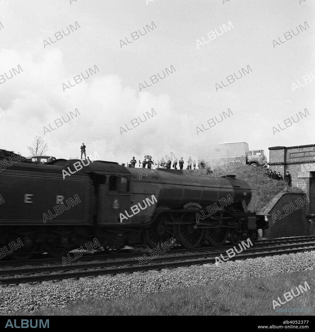 The 'Flying Scotsman' passing under a bridge at speed, near Selby, North Yorkshire, 1968. The 'Flying Scotsman', seen passing under a bridge on the A19 between Selby and York, is a steam locomotive designed by Sir Nigel Gresley and built in Doncaster in 1923. It was famous for hauling the first non-stop train between London and Edinburgh in 1928. The photograph was taken five years after the locomotive was withdrawn from service by British Railways and sold for preservation. By this time the 'Flying Scotsman' was the last remaining loco of its class. Seventy similar locos were scrapped, many being sent to the yards of Barry Island in Wales where they stood for a number of years. The 'Flying Scotsman' went on tour of the United States and returned to the UK in 1973. By 1995, the locomotive had been dismantled and lay in pieces at the Southall depot in West London. The high cost of restoration meant that a buyer had to be sought and businessman Tony Marchington bought it for a cost of £2.5m. The engine was rebuilt and it made its first run in October of 1999 to Edinburgh.