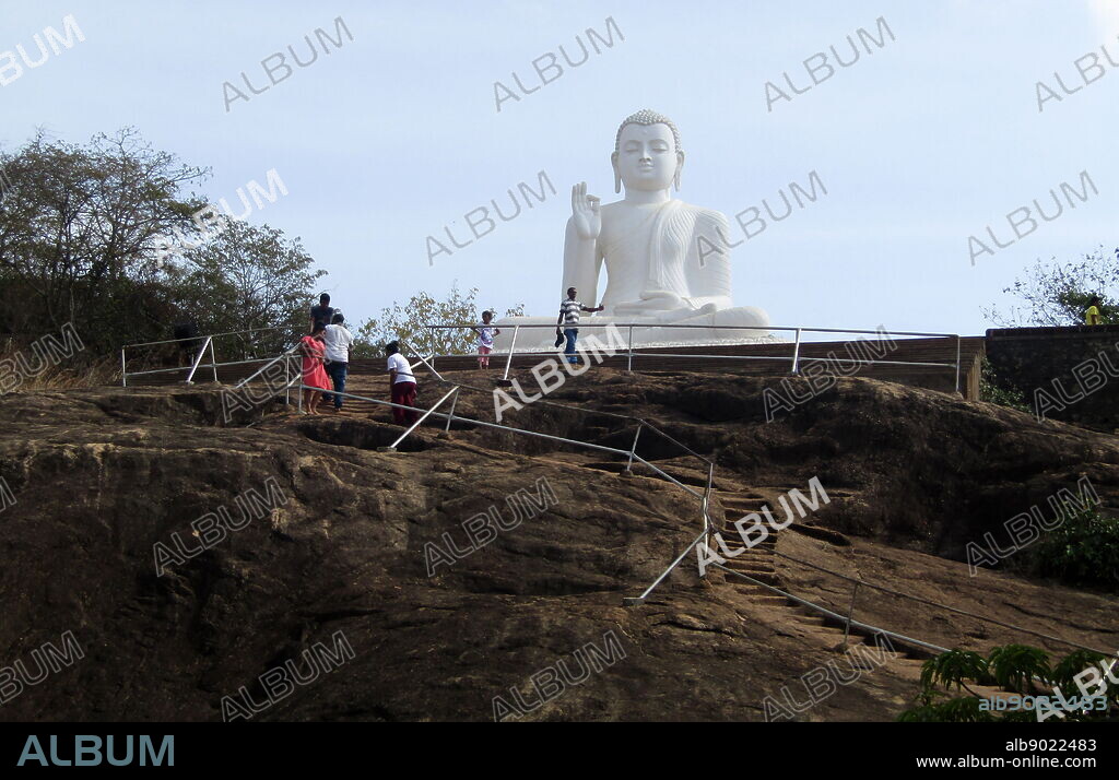 rock-carved steps leading to a large white Buddha statue. Mihintale is a mountain peak near Anuradhapura in Sri Lanka. It is believed by Sri Lankans to be the site of a meeting between the Buddhist monk Mahinda and King Devanampiyatissa which inaugurated the presence of Buddhism in Sri Lanka.