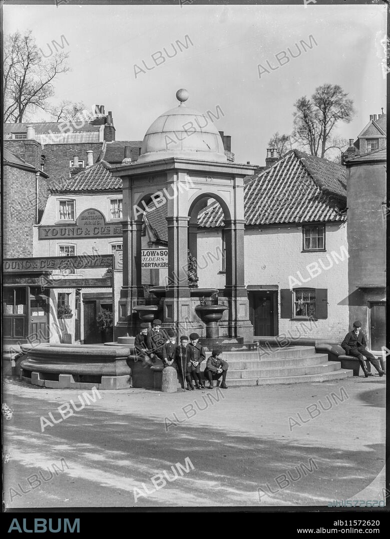 WILLIAM O FIELD. Drinking Fountain, Roehampton Lane, Roehampton, Wandsworth, Greater London Authority, 1904. A group of young boys gathered on the steps at the base of the drinking fountain at the junction of Medfield Street and Roehampton Lane with the Montague Arms visible in the background. The fountain was built in 1882 to the designs of Sir Frederick Lance for Mrs Lyne Stephens of Grove House. A detail from this photograph appears in 'William Fields's Photographs of Putney', compiled by Dorian Gerhold and Michael Bull for the Wandsworth Historical Society.