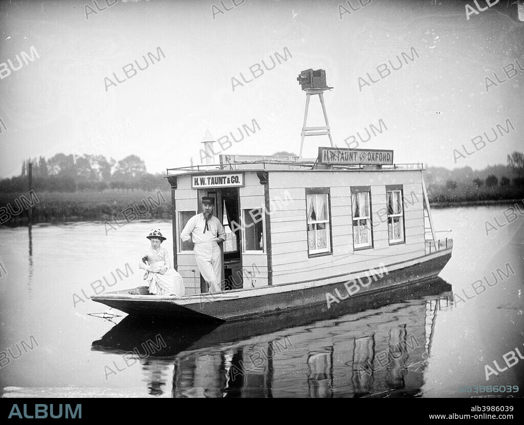 Henry Taunt on his floating studio near Oxford, Oxfordshire, 1895. Henry Taunt is pictured on the houseboat which he used for river photography with a lady, probably his close friend Fanny Miles.