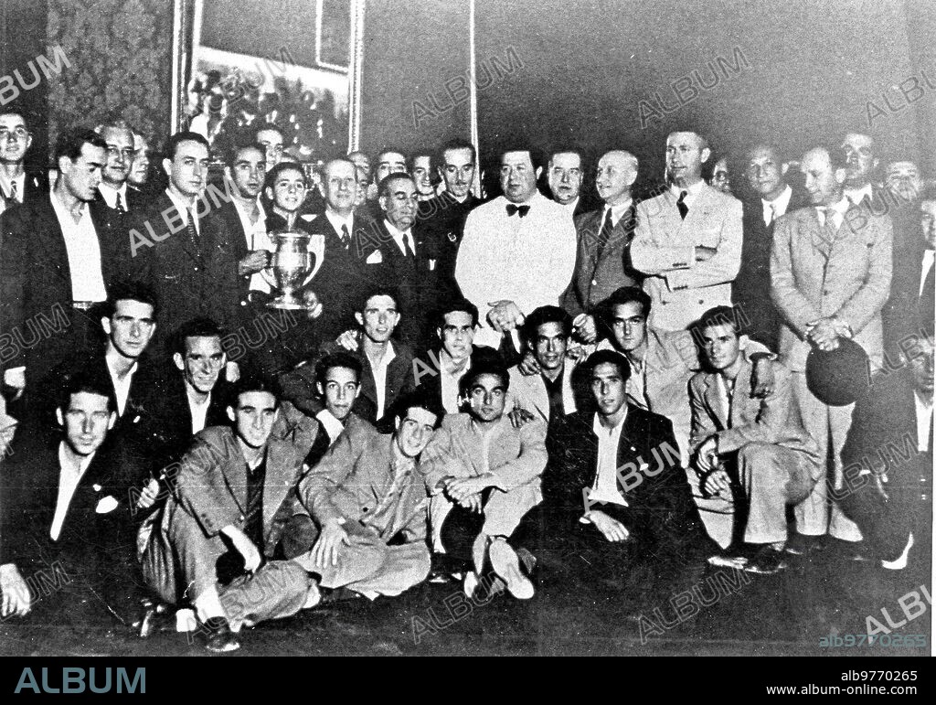Recepción municipal al Sevilla F. C., cuyo primer equipo conquistó la I Copa del Generalísimo en el año 1939, tras derrotar por 6-2  al Racing de Ferrol en el estadio de Montjuic de Barcelona en partido disputado el día 25 de junio.  En la imagen, Campanal I, capitán del equipo sevillista, porta el trofeo. Al centro, con americana blanca y pajarita, se ve a Enrique Balbontín de Orta, alcalde de la ciudad en 1939 y presidente que fue del Sevilla entre 1920 y 1921. También se reconoce a Ramón Sánchez-Pizjuán, que era presidente del club de Nervión en esos años.
