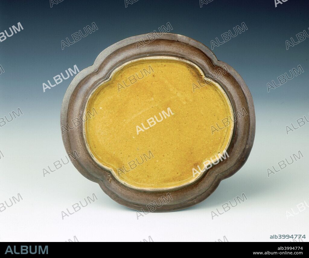 A pair of aubergine kinrande four-lobed shallow dishes gilded with a central Shou (longevity) character among peach branches within plain borders. The rim is decorated with gilt bands. The piece is primarily covered with an aubergine glaze, the base, however, is glazed yellow. Kinrande refers to the gold brocade decoration forming the pattern against the monochrome background colour.