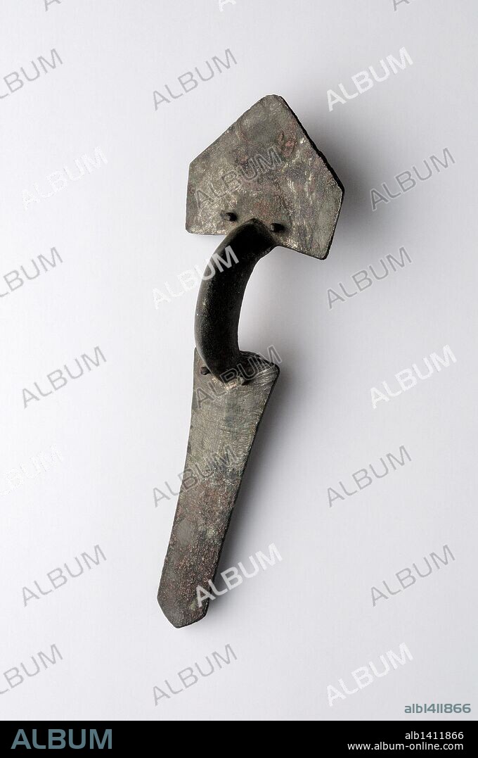Fíbula trilaminar de arco en bronce, formada por tres piezas martilladas y unidas por clavos .Dimensiones 10, 2 x 3, 1 cm Altura 2 cm (Siglo V dc ) - Epoca Visigoda , procedente de la " Necrópolis de Afligidos " - Yacimiento arqueológico de Complutum en Alcalá de Henares ( Madrid ). ESPAÑA .