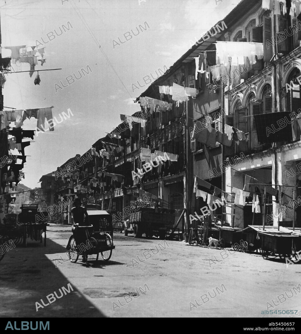 It rains at least one every afternoon, usually many times, in Singapore soon as rain stops, clothes are hung out to dry on bamboo poles. January 20, 1951 (Photo By Horace Bristol, East - West Photographic Agency).