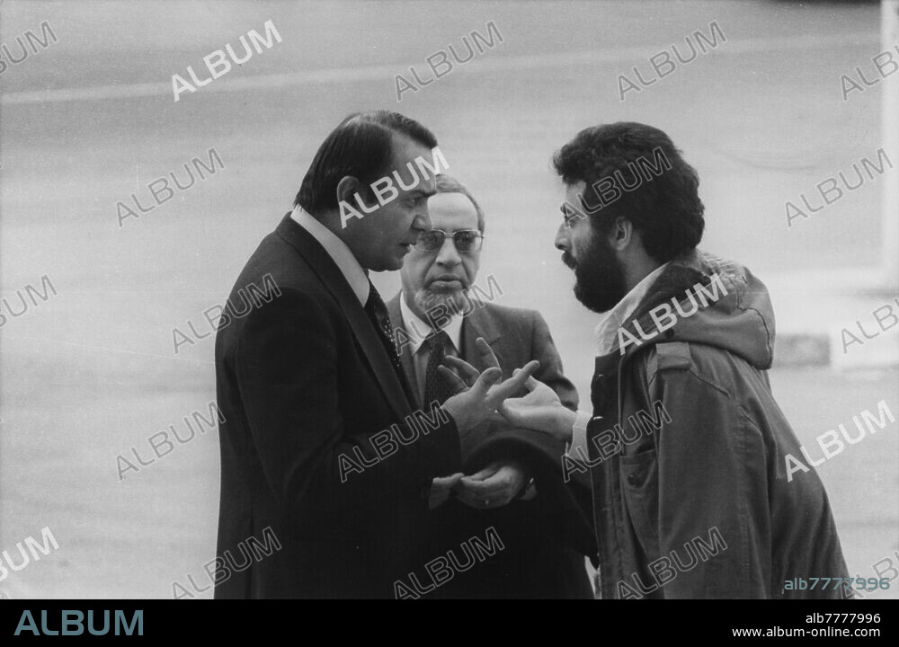 Iranische Revolution / Geiselnahme in der amerikanischen Botschaft in Teheran vom 4. November 1979 bis 20. Januar 1981. Der iranische Außenminister Sadegh Ghotbzadeh (l.) und der Ko-Vorsitzende der Untersuchungskommission der Vereinten Nationen im Iran, Mohammed Bedjaoui (M.), auf dem Flughafen Teheran im Gespräch mit einem iranischen Studenten über die Freilassung der Geiseln. Foto, 11.03.1980.