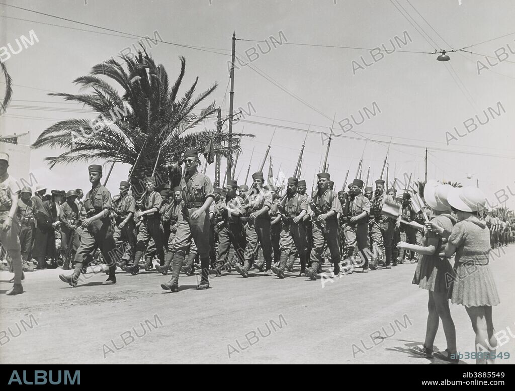 May 20, 1943 - Two French children waving as French troops march by in the allied victory parade along Avenue Gambetta in Tunis, Tunisia.