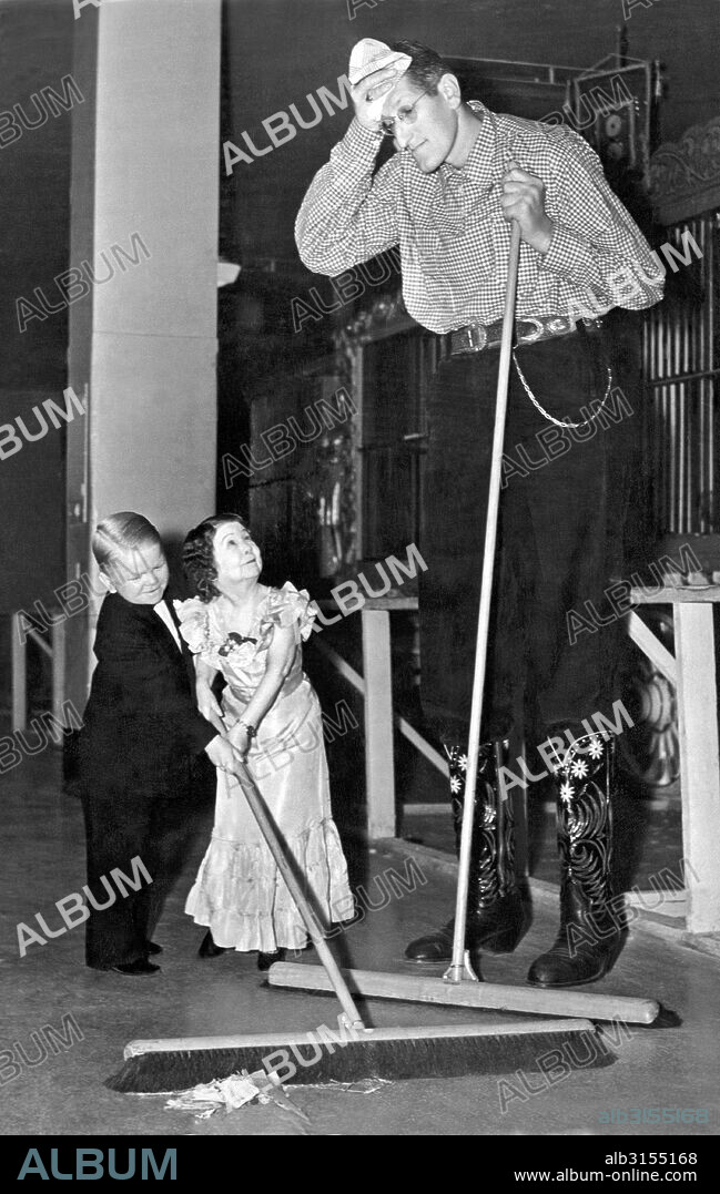 United States:  c. 1938. Robert Wadlow, the world's tallest man, share sweeping duties with two members of the Doll family  while on tour with the Ringling Brothers/Barnum & Bailey Circus.