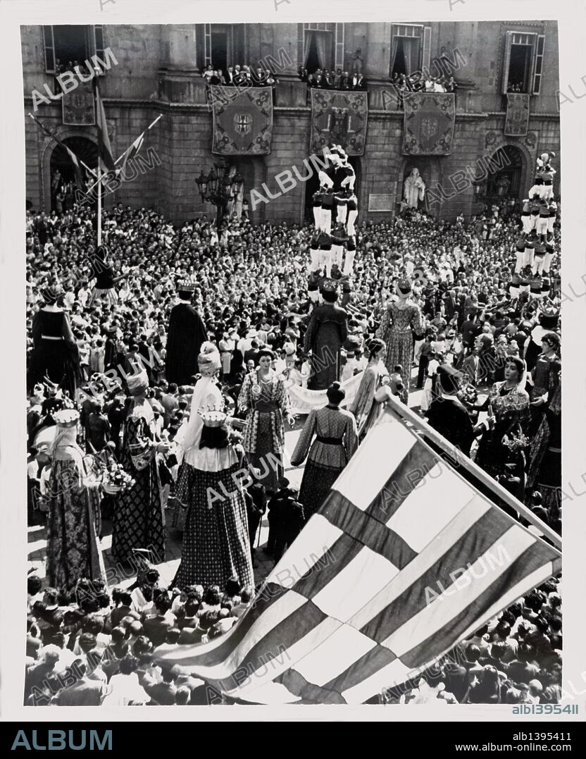 Baile de gigantes y "castellers" en la Plaza de San Jaime de Barcelona frente al edificio del Ayuntamiento. Años 1950.