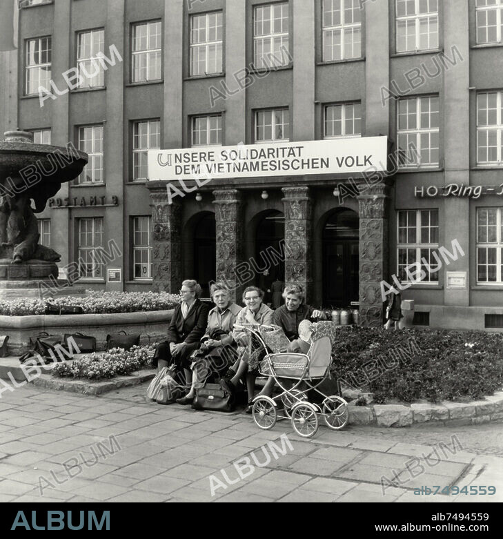 Geschichte: Deutschland / DDR. Frauen mit Kinderwagen vor dem Ring-Messehaus am Tröndlinring in Leipzig (Sachsen) mit Propagandaspruch "Unsere Solidarität dem vietnamesischen Volk" an der Fassade. Foto, 1968.